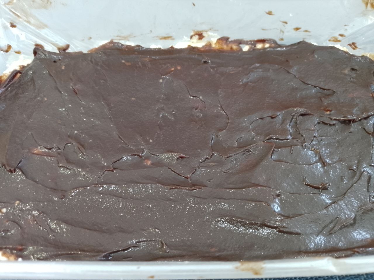 Десерт из творога, изюма и кураги, в шоколадной глазури: Сверху творожную массу равномерно покрываем оставшейся шоколадной глазурью. Форму с творожной массой ставим в