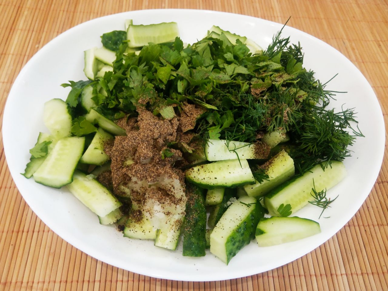 Салат из свежих огурцов, чеснока и зелени, просто и вкусно: Соединяем в емкости огурцы, зелень петрушки и укропа, измельченный чеснок, молотый черный перец и соль по