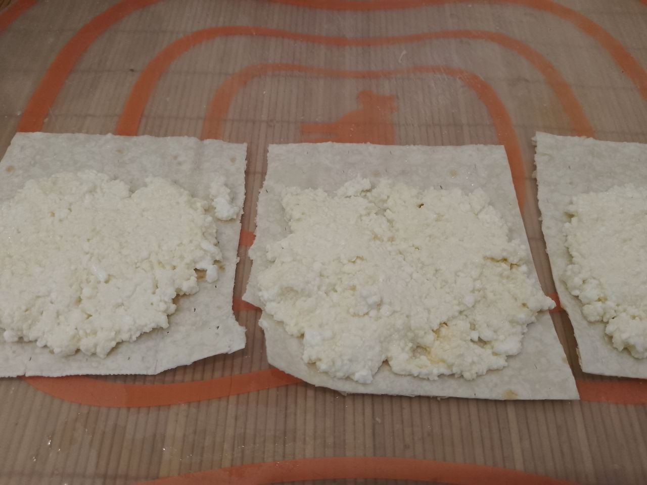 Лаваш с творожной начинкой и ягодами, на сковороде: На полоски кладем творог, разравниваем, края смачиваем водой.