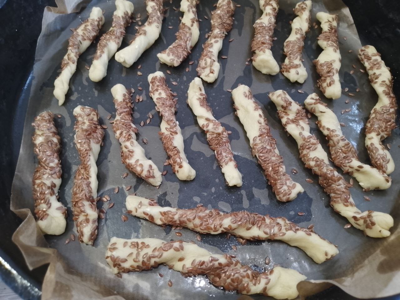 Печенье с кунжутом и семенами льна, приготовленное из теста с вареными яйцами: Застилаем противень пергаментом и выкладываем на него полоски.
