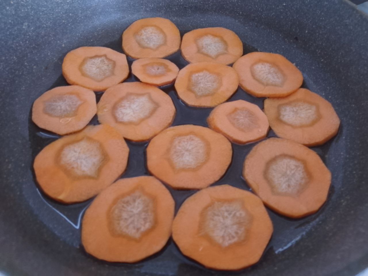 Морковь жареная на растительном масле, со специями, на сковороде: Сковороду разогреваем с растительным маслом и выкладываем кружочки моркови.