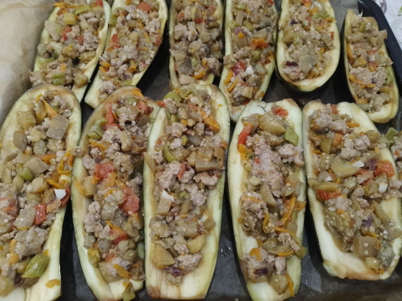 Запеченные в духовке, баклажаны с овощами, фаршем и сыром: Наполняем начинкой середину баклажанов и укладываем на противень застланный пергаментом.