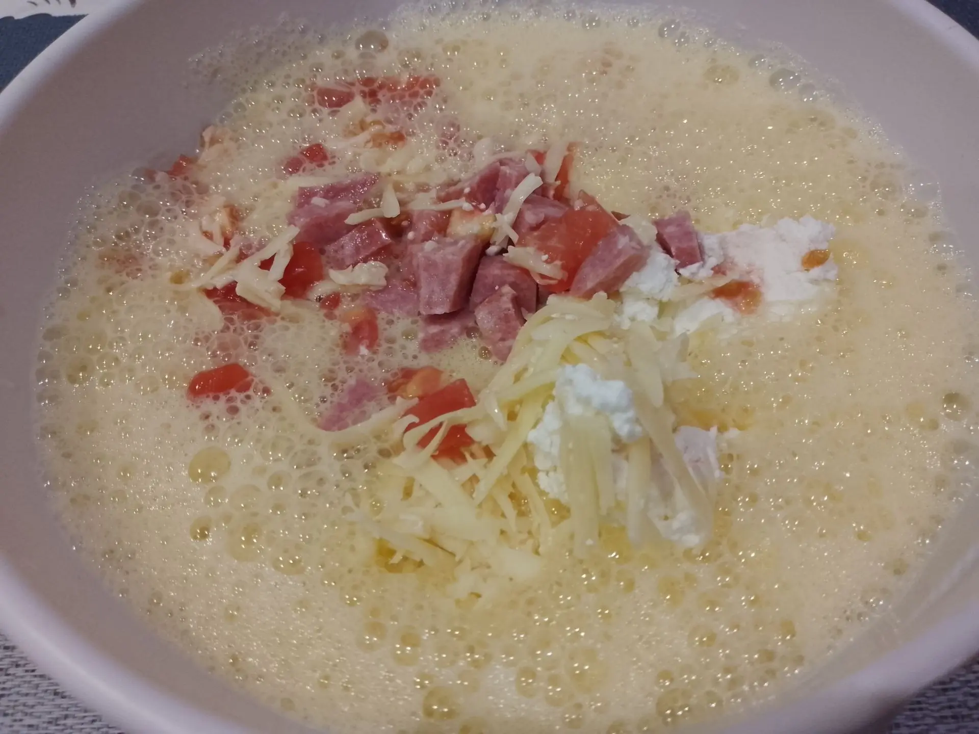 Вкусный завтрак из яиц, творога, помидоров и колбасы или ветчины: Добавляем измельченную ветчину или колбасу и помидоры, размешиваем.