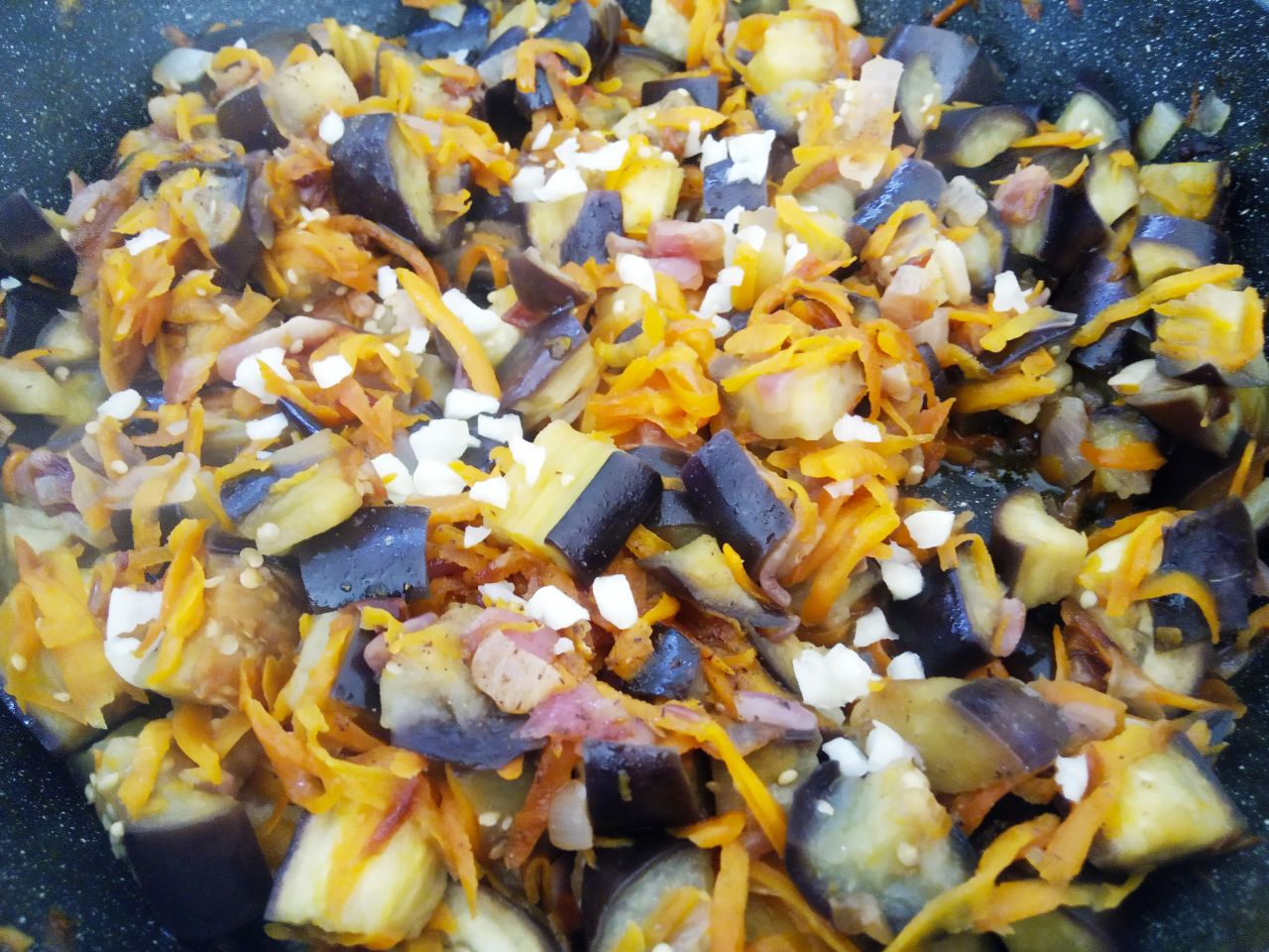 Баклажаны с луком и морковью, тушеные на сковороде: Закрываем сковороду крышкой и тушим до размягчения баклажан. В конце тушения добавляем чеснок, перемешиваем.