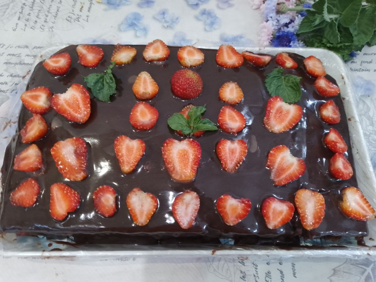 Шоколадный пирог на молоке с клубникой, покрытый шоколадной глазурью: Сверху пирог украшаем ягодами клубники и помещаем в холодильник для застывания глазури.