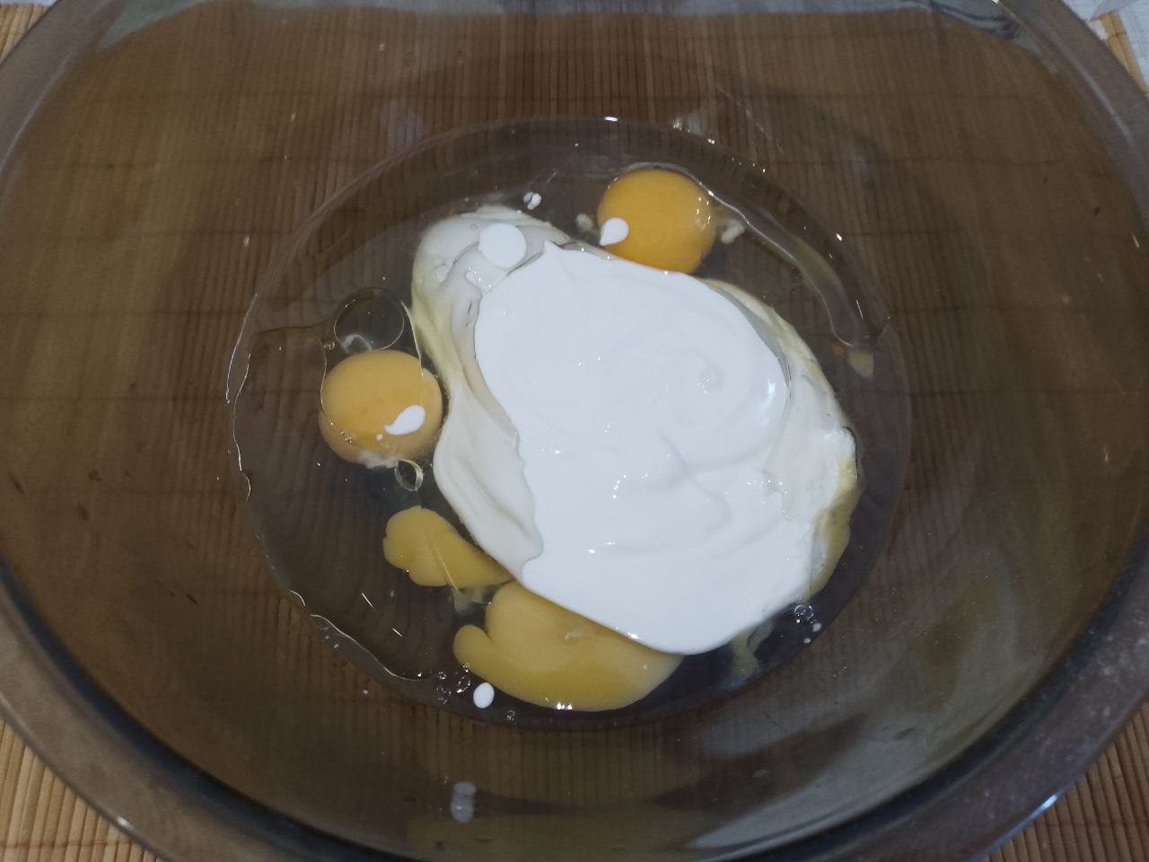 Пирожки из дрожжевого теста на сметане, с мясной начинкой, жареные на сковороде: В посуду для замешивания теста разбиваем яйца, добавляем растительное масло и сметану, размешиваем.