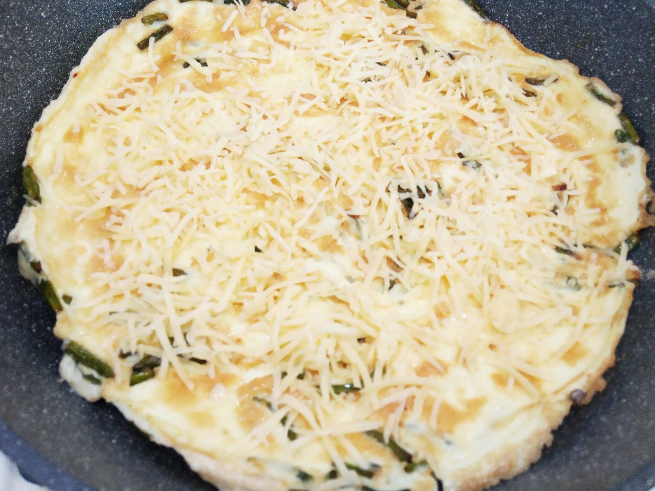 Вкусный и аппетитный завтрак из омлета, чесночных стрелок и сыра: Омлет посыпаем тертым сыром, сворачиваем вдвое и выдерживаем на сковороде пару минут.