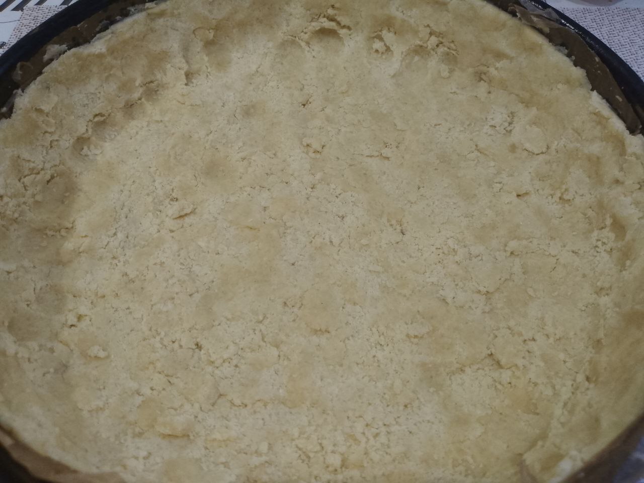 Пирог из песочной крошки, с творожной начинкой и замороженными ягодами: Форму застилаем пергаментом и распределяем крошку, образуя бортики. Форму с тестом ставим на 30 минут в