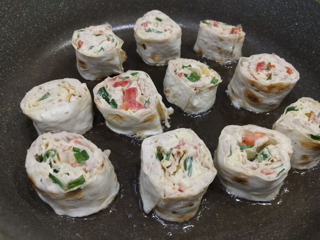 Вкусная закуска из лаваша, куриного филе и сыра, на сковороде: Разогреваем сковороду с растительным маслом и укладываем рулеты разрезанной стороной.