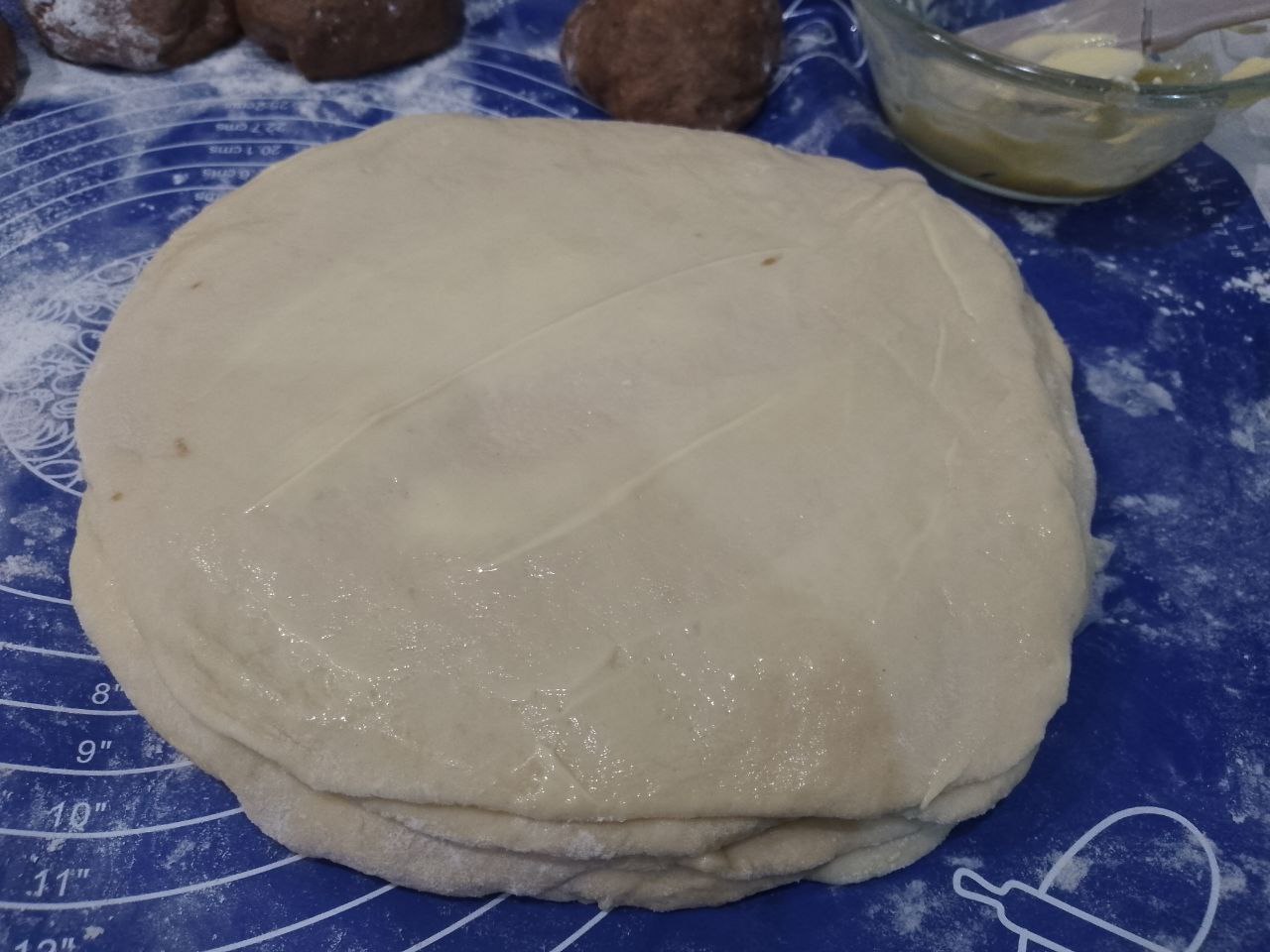 Булочки из слоеного теста с корицей и изюмом: Также раскатываем все части теста, смазываем маслом и складываем один на другой.