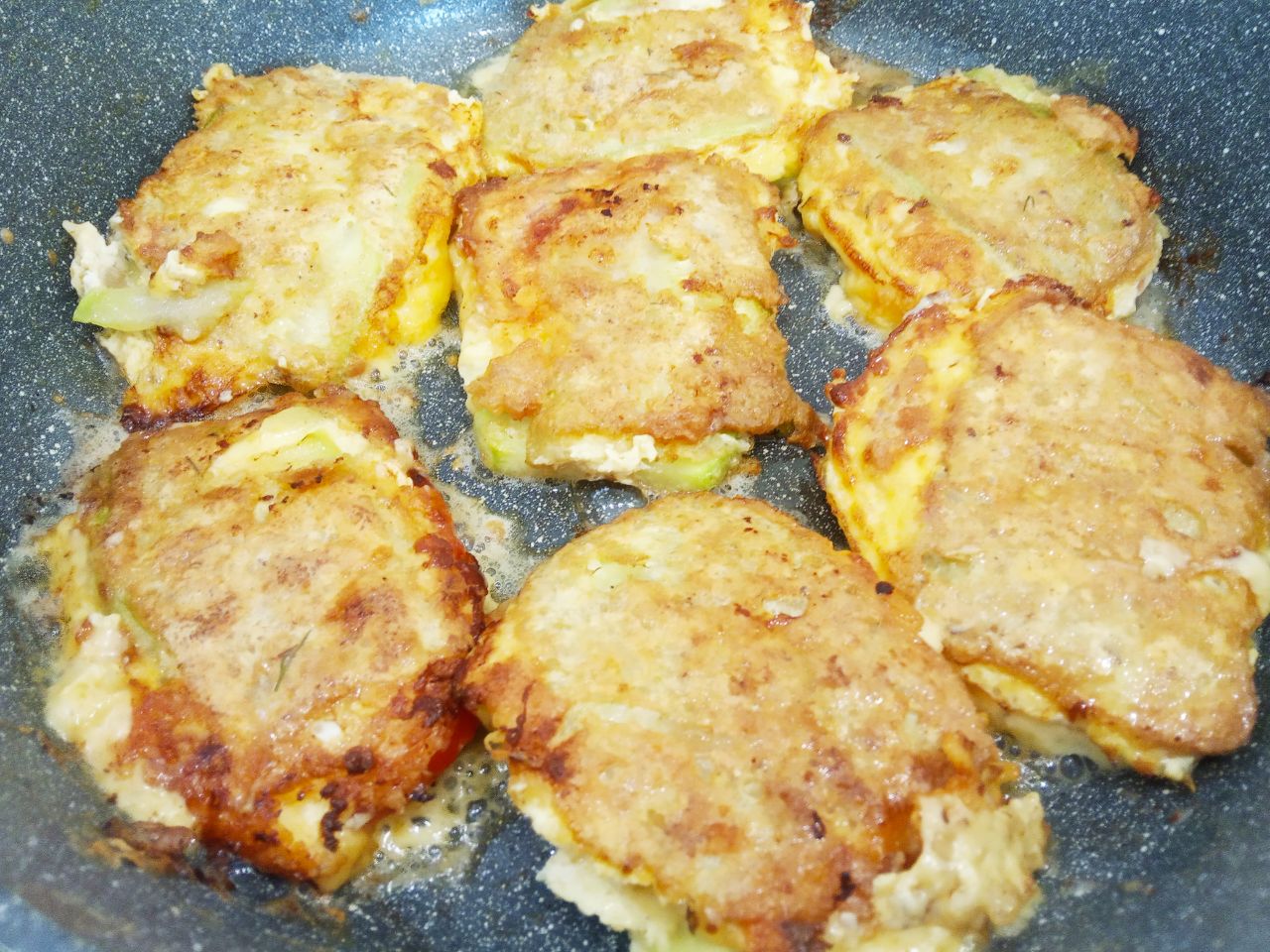 Кабачки с начинкой из помидоров и сыра, жареные в яичном кляре: Полоски с начинкой окунаем во взбитые яйца и укладываем на сковороду.