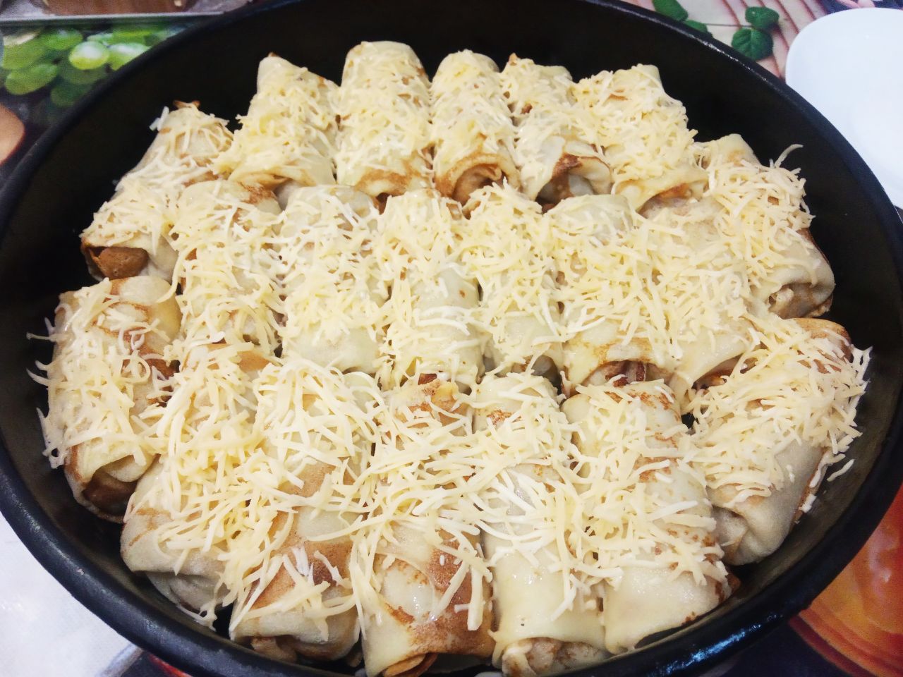 Блинчики с мясом и сыром, запеченные в духовке: Достаем противень с блинчиками из духовки и посыпаем тертым сыром.