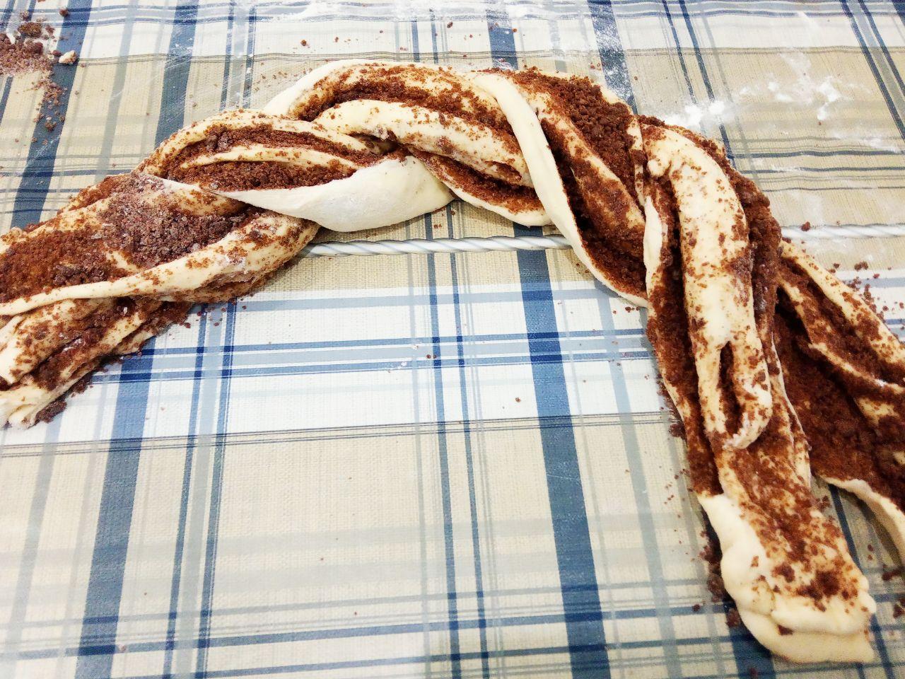 Пирог из дрожжевого теста с шоколадной крошкой: Сворачиваем тесто рулетом и разрезаем на две части. Рулет заплетаем косичкой разрезанной стороной кверху и