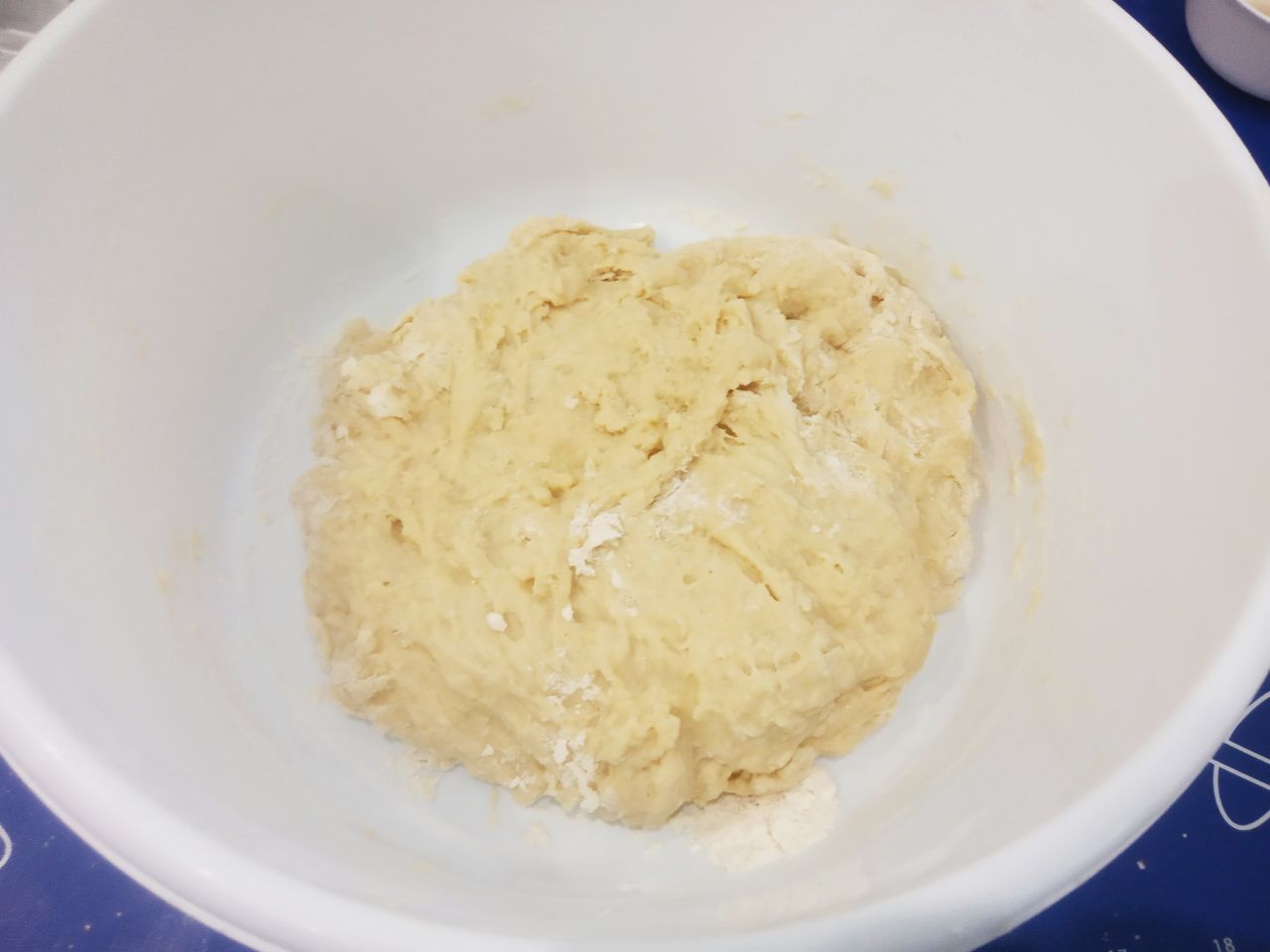 Булочки с начинкой из яблок и мака: Больше половины просеянной муки всыпаем в тесто, тщательно размешиваем лопаткой.