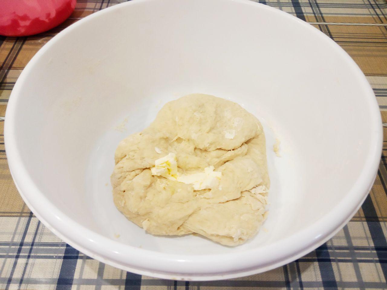 Жареные пончики без яиц с начинкой и с кунжутом: Размягченное сливочное масло кусочками кладем в середину теста и вымешиваем до нежного теста.