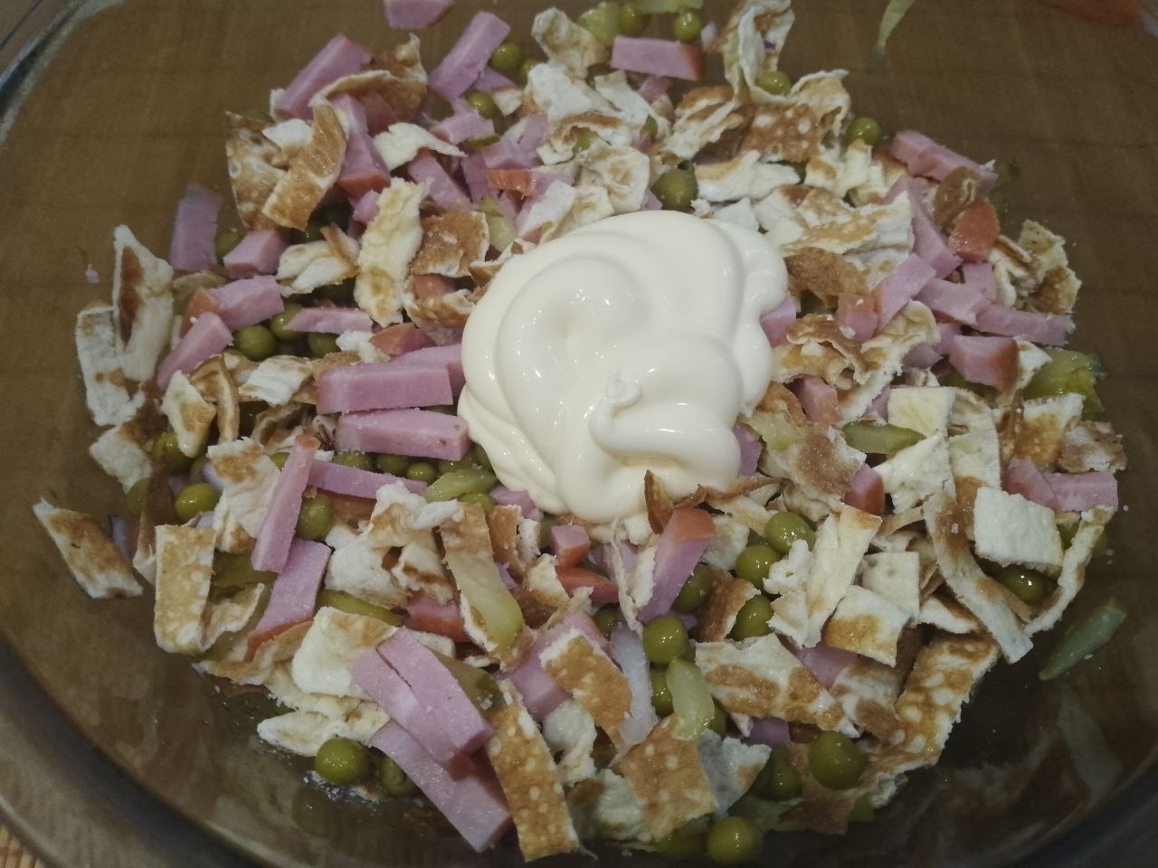 Сытный, вкусный и аппетитный салат из яичных блинов, ветчины и других ингредиентов: В чашу выкладываем все ингредиенты, добавляем соль по вкусу и майонез, перемешиваем.
