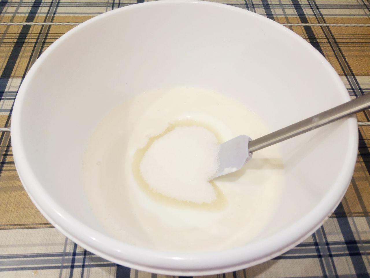 Жареные пончики без яиц с начинкой и с кунжутом: Всыпаем сахар, вливаем кефир и размешиваем.