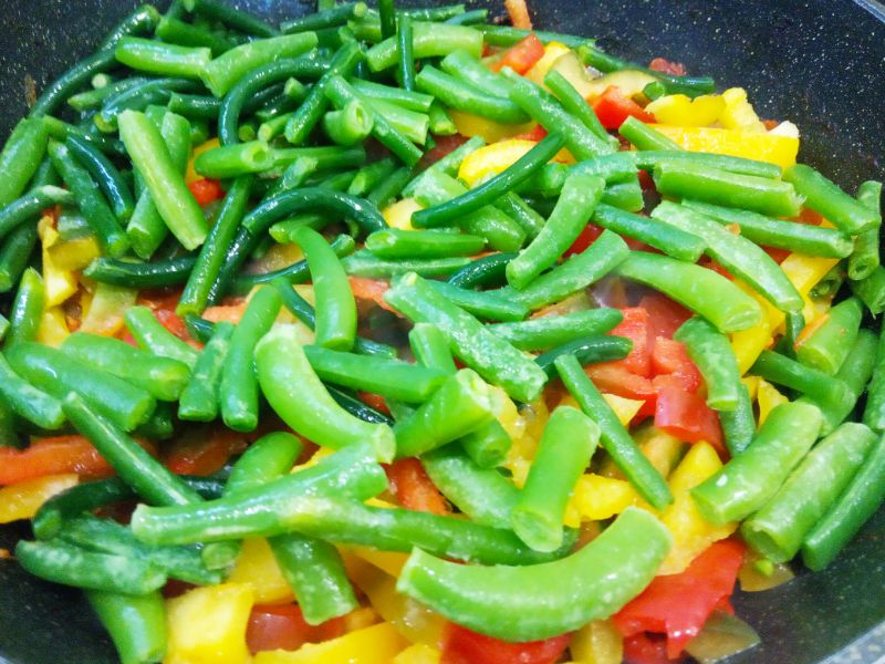 Тушеные замороженные овощи, полезно и вкусно: Кладем в сковороду полоски перца, стрелки чеснока, спаржевую фасоль и два лавровых листочка. Овощи