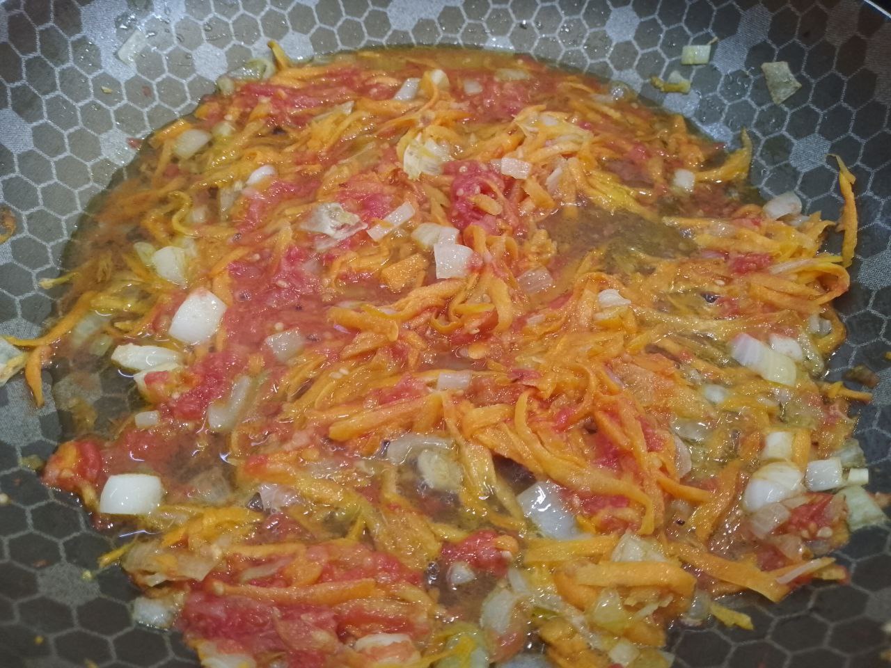 Острые чесночные стрелки с зеленым горошком и овощами, на сковороде: Добавляем тертые помидоры и тушим около 3 минут.
