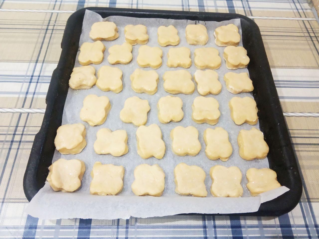 Печенье домашнее к чаю, мягкое и вкусное: Противень застилаем пергаментом и укладываем печенье. Один белок взбиваем и смазываем кондитерской кисточкой