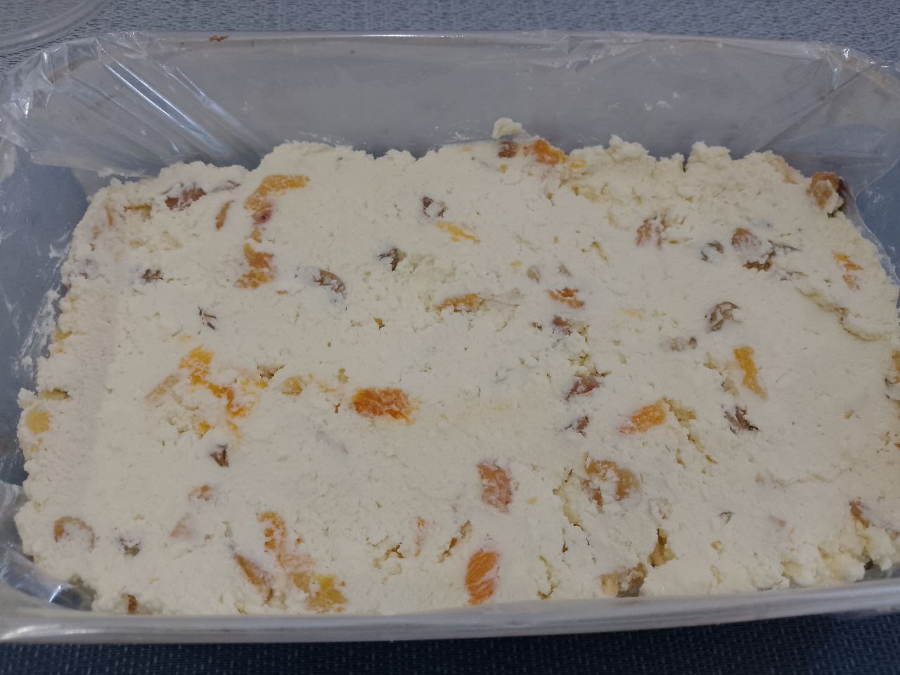 Десерт из творога, изюма и кураги, в шоколадной глазури: Достаем форму с застывшей глазурью и выкладываем творожную массу, разравниваем.