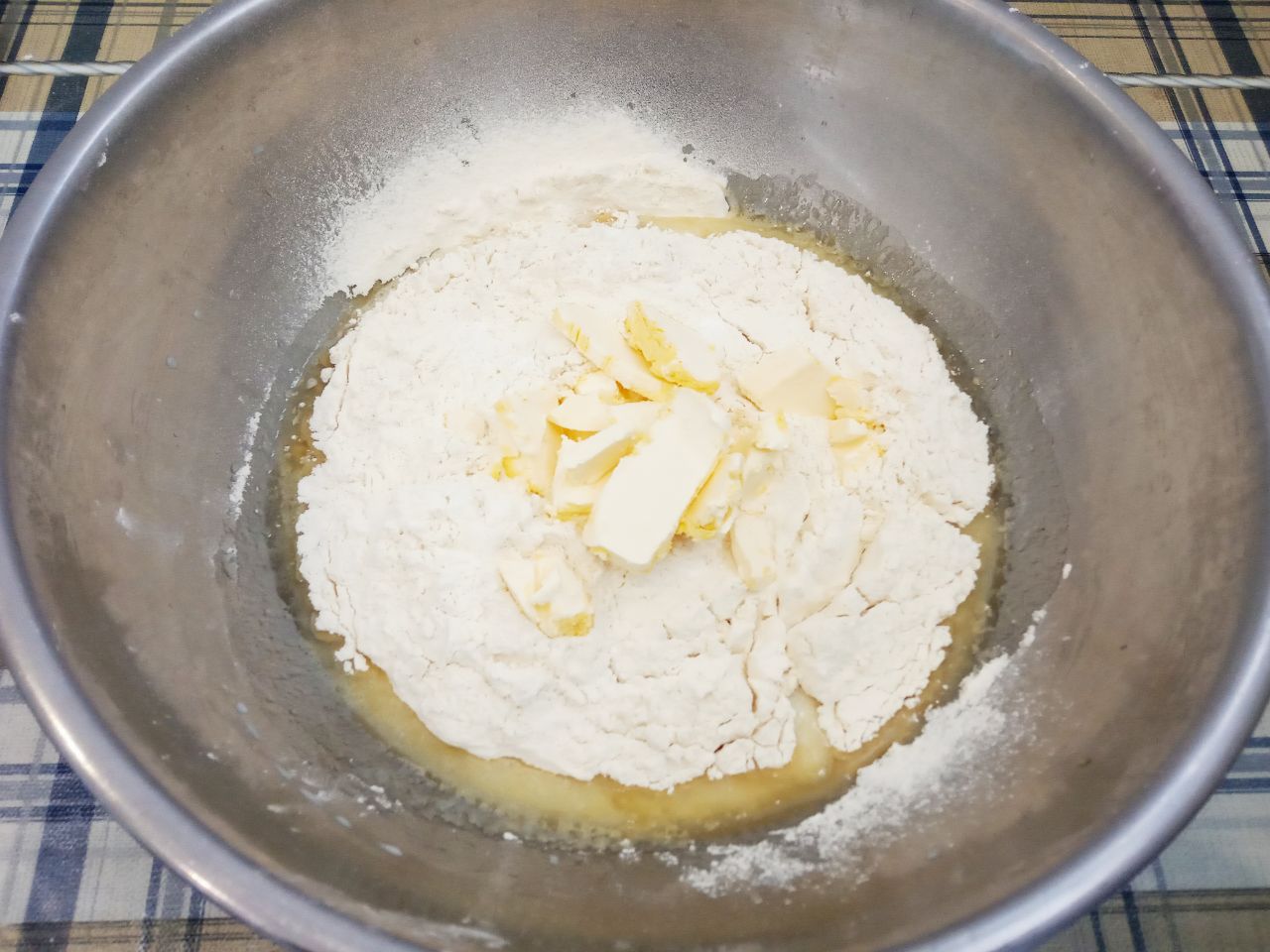 Булочки с изюмом из сдобного дрожжевого теста, воздушные и нежные: Кладем кусочками размягченное сливочное масло и замешиваем мягкое и нежное тесто.