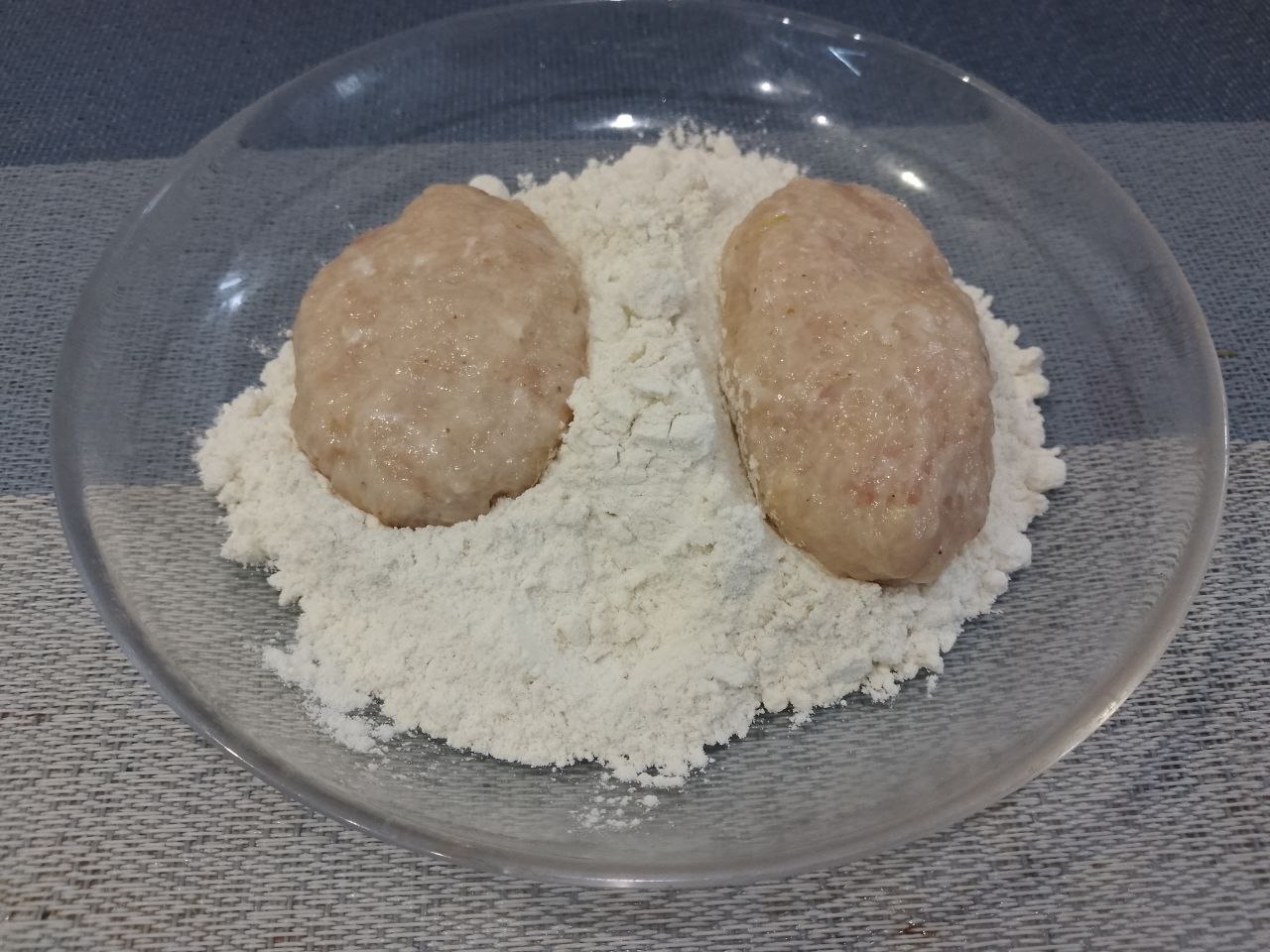 Котлеты из куриного мяса в яичном кляре и панировочных сухарях: Каждую котлету обваливаем в муке, чтобы она равномерно покрыла поверхность.