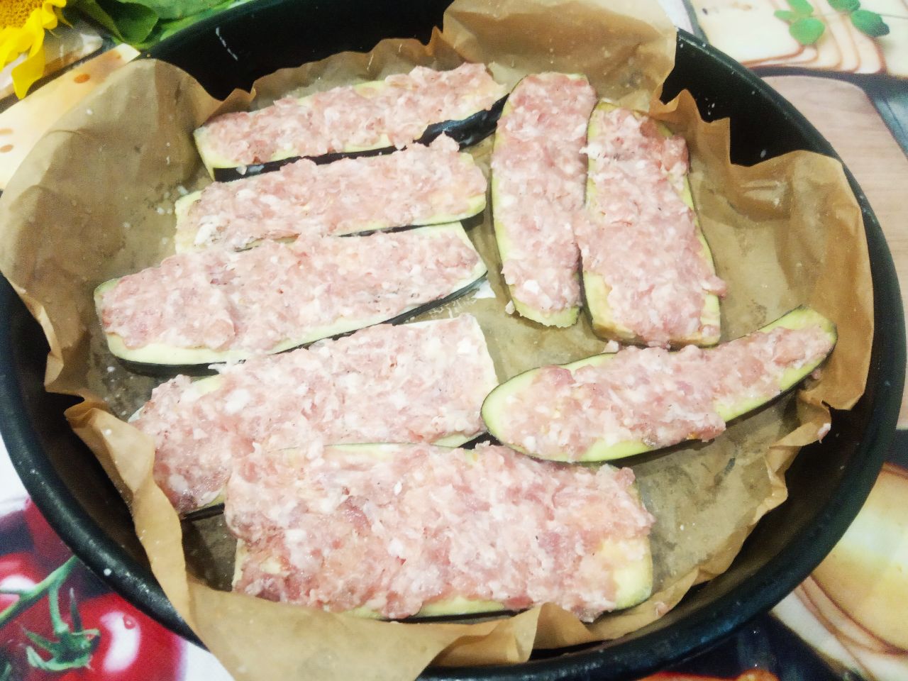 Запеченные баклажаны с фаршем, помидорами и сыром, в духовке: Баклажаны промываем водой, распределяем равномерно фарш и укладываем на противень застланный пергаментом.
