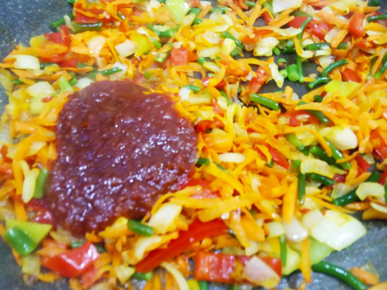 Красная чечевица тушеная с овощами и мясными шариками: Добавляем томатную пасту, перемешиваем.
