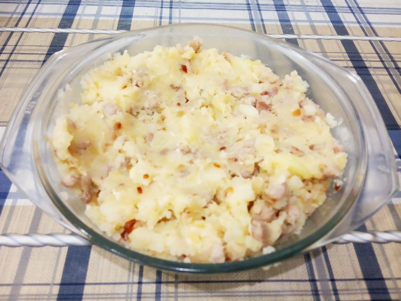 Картофель фаршированный начинкой и запеченный в духовке: Картофель тщательно разминаем толкушкой. Выкладываем обжаренный фарш и хорошо размешиваем.