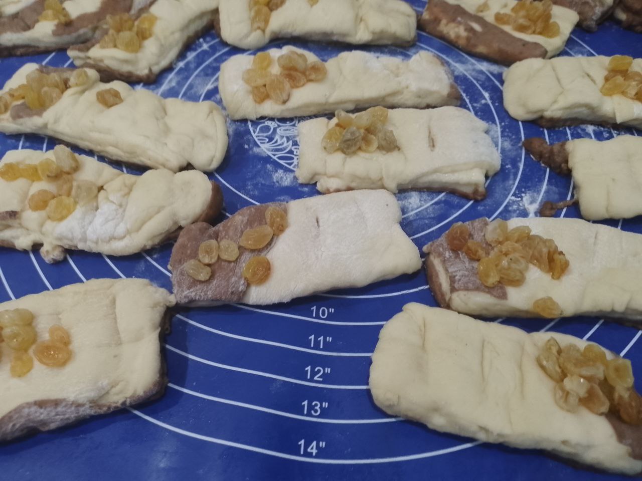 Булочки из слоеного теста с корицей и изюмом: Переворачиваем прямоугольники светлой стороной, посыпаем корицей с сахаром половину прямоугольников,