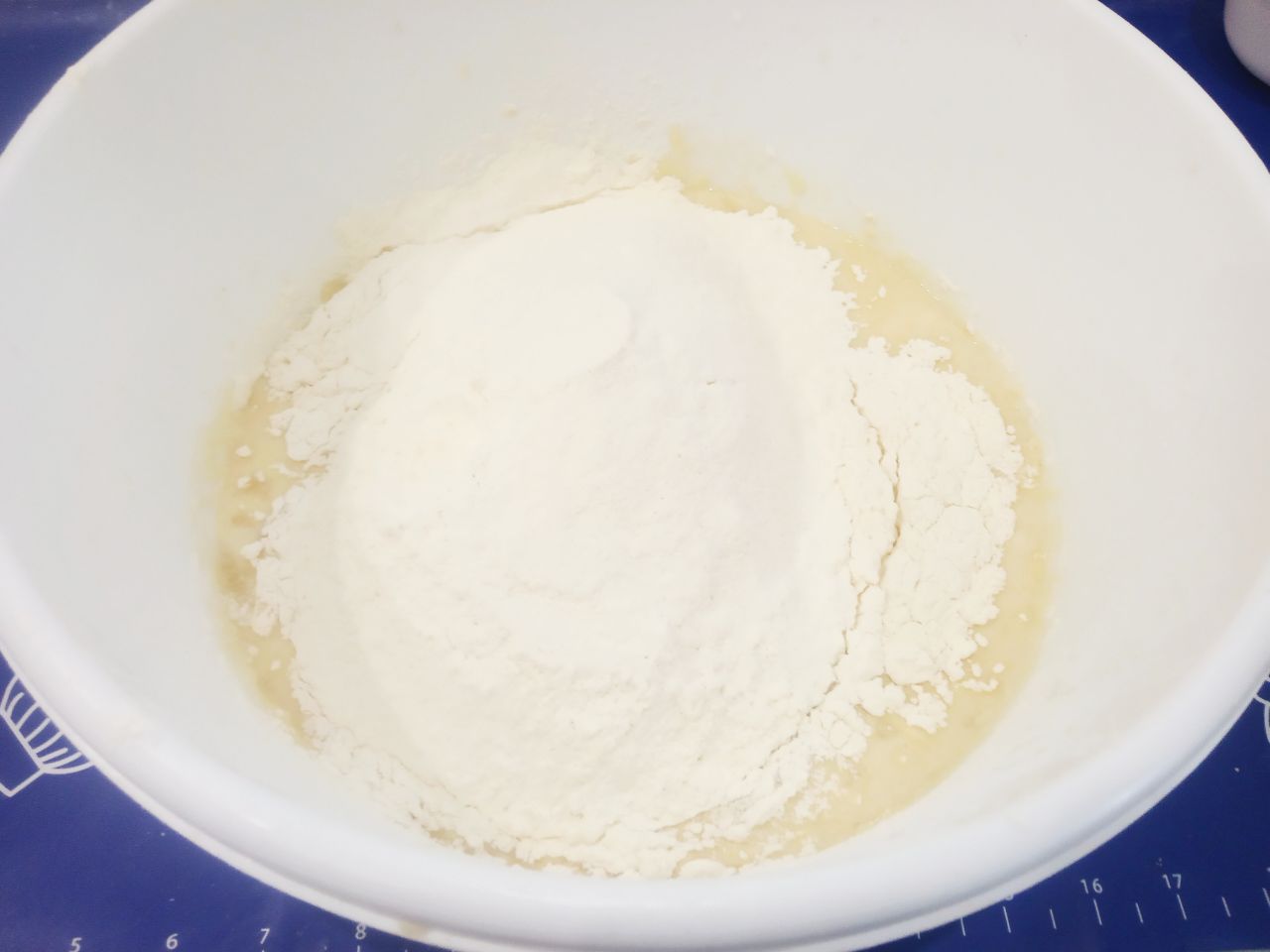 Булочки с начинкой из яблок и мака: Больше половины просеянной муки всыпаем в тесто, тщательно размешиваем лопаткой.