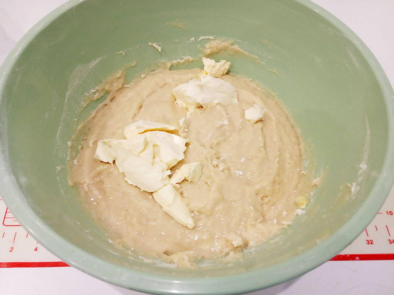Булочки с изюмом в мучной крошке, воздушные и вкусные: Кладем в тесто кусочками размягченное сливочное масло и размешиваем.