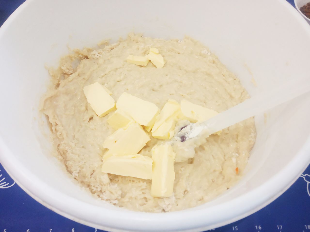 Булочки с начинкой из жареных яблок, изюма и корицы: В размешанное тесто кладем кусочки размягченного сливочного масла, перемешиваем и добавляем оставшуюся муку.