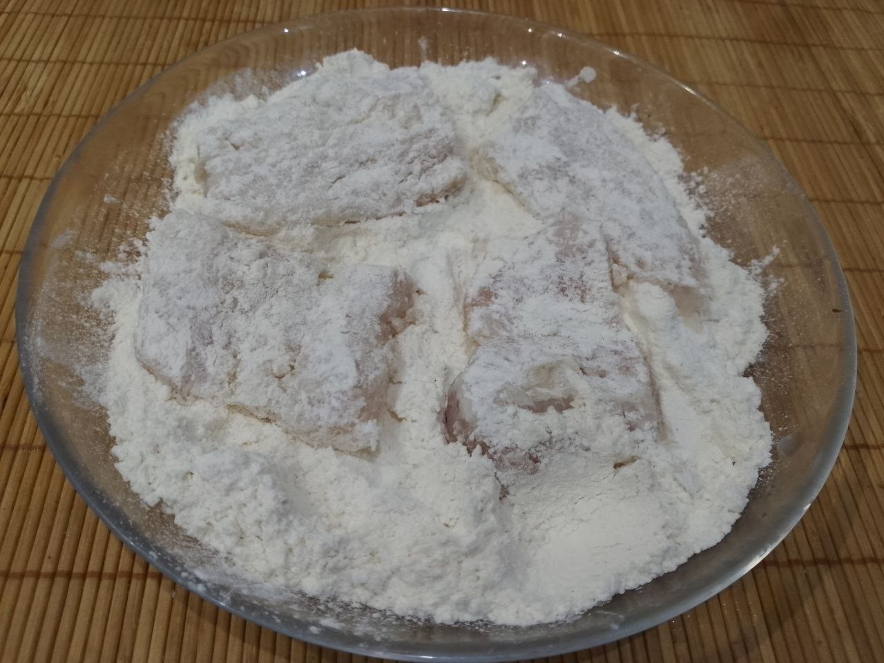 Филе минтая в кляре, простое и вкусное блюдо: В тарелку насыпаем муку. Кусочки филе обваливаем в муке.