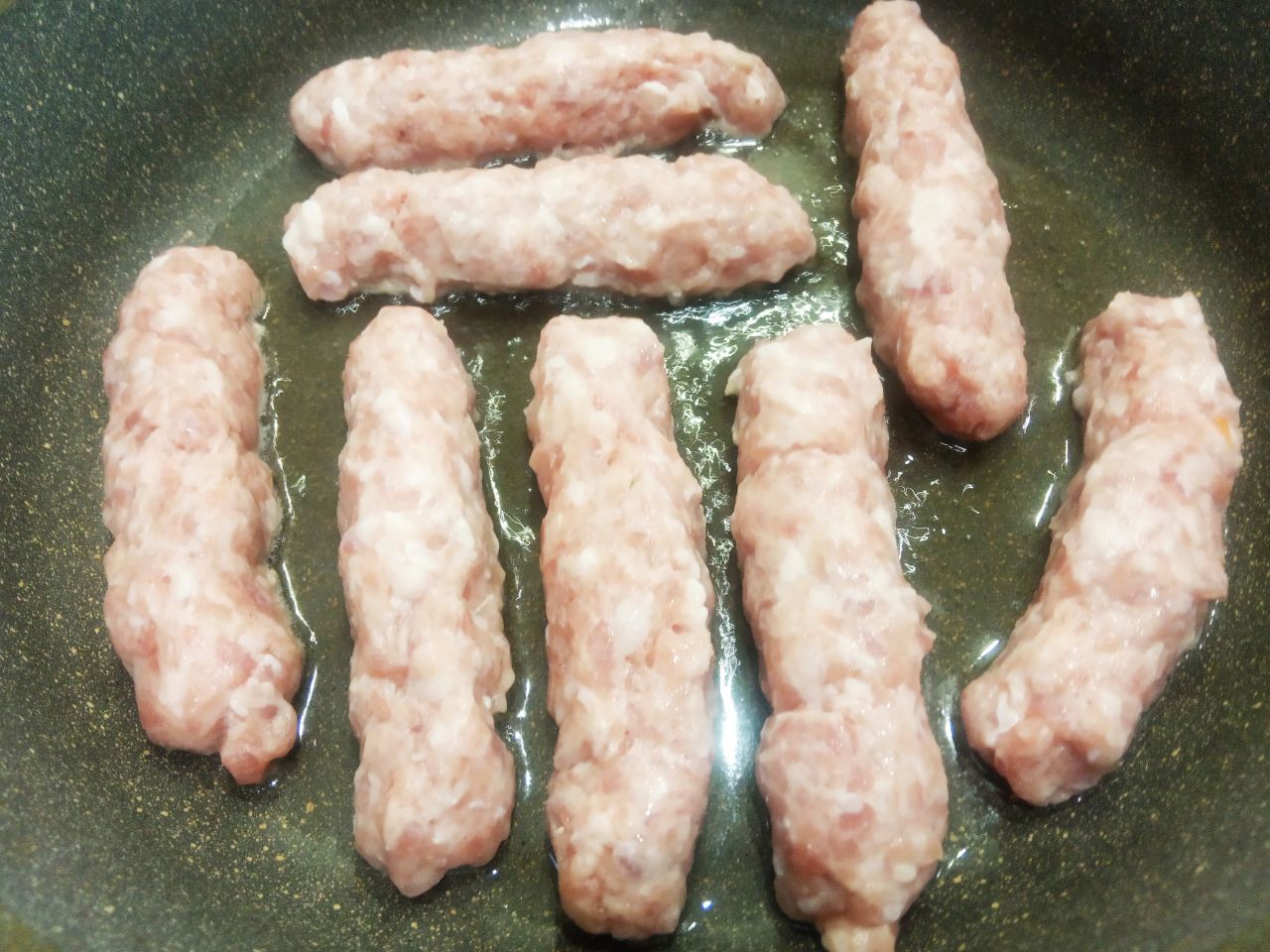 Мясные колбаски, жареные на сковороде, вкусные и аппетитные: Разогреваем сковороду с растительным маслом и укладываем колбаски.