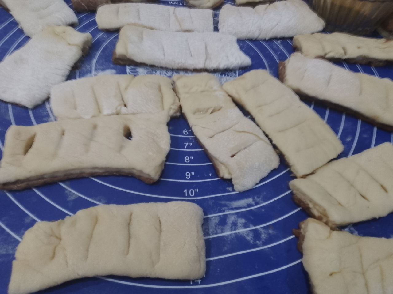 Булочки из слоеного теста с корицей и изюмом: Переворачиваем прямоугольники светлой стороной, посыпаем корицей с сахаром половину прямоугольников,