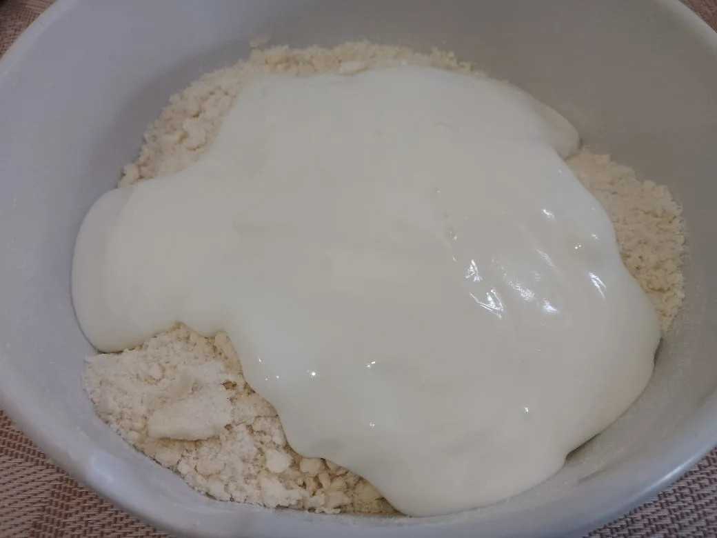 Простой рецепт печенья с кокосовой стружкой, без яиц: Добавляем сметану и замешиваем мягкое и нежное тесто. Тесто накрываем пленкой и ставим в холодильник на