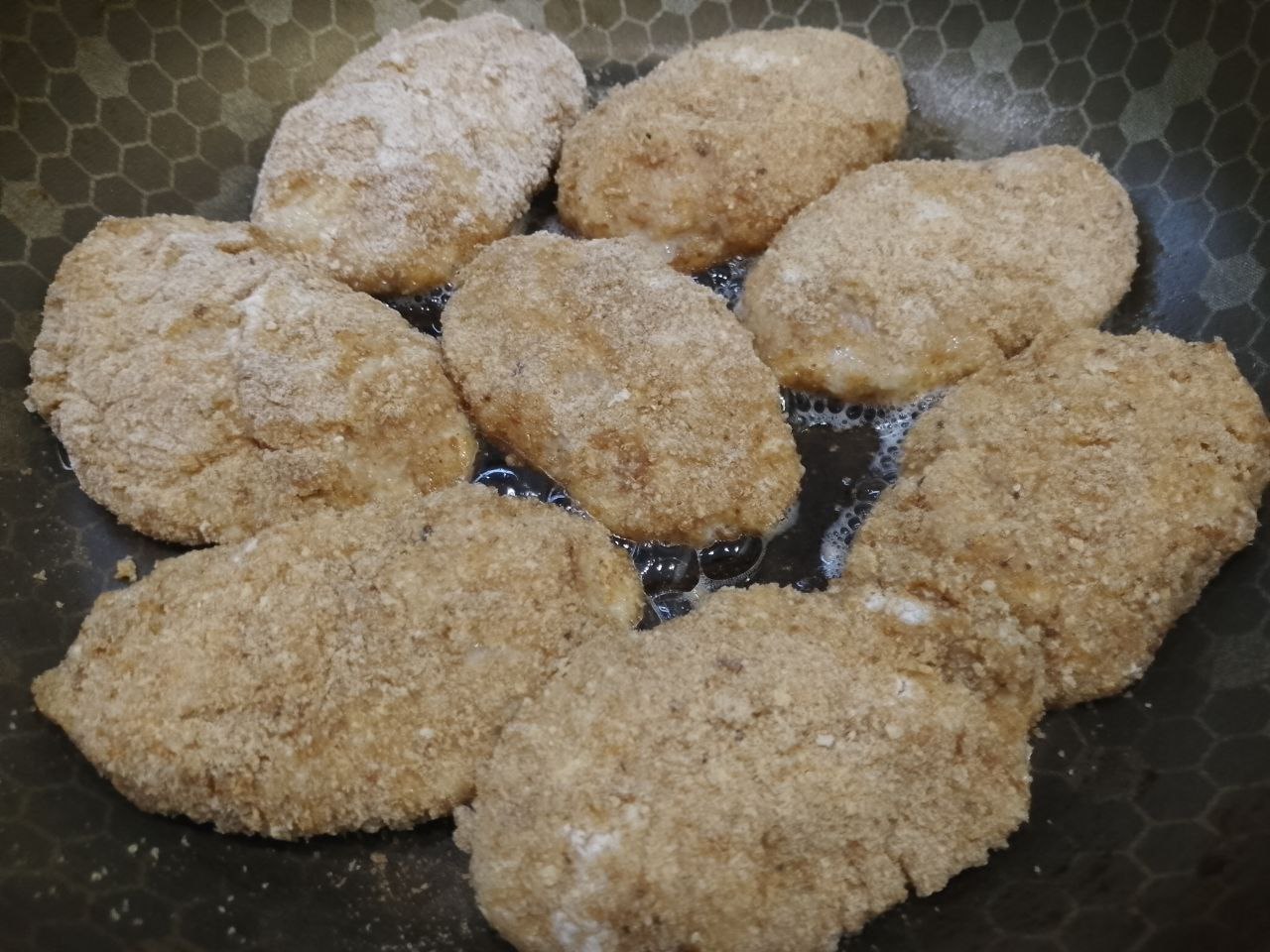 Котлеты из куриного мяса в яичном кляре и панировочных сухарях: Сковороду разогреваем с растительным маслом и выкладываем котлеты. Обжариваем их на среднем огне под крышкой