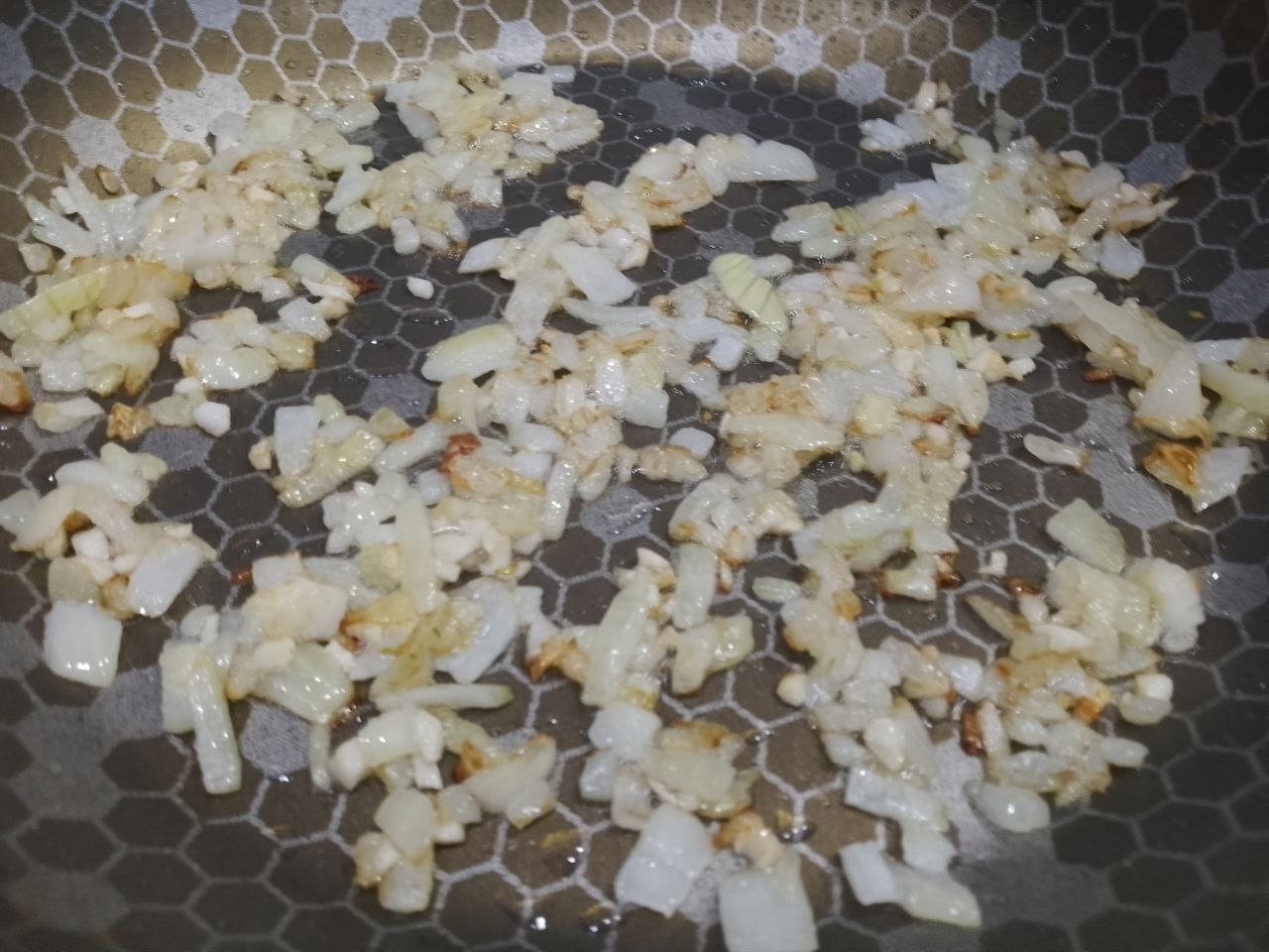 Макаронная запеканка с курицей, сыром и помидорами: Разогреваем сковороду с растительным маслом, обжариваем лук с чесноком до золотистого цвета.