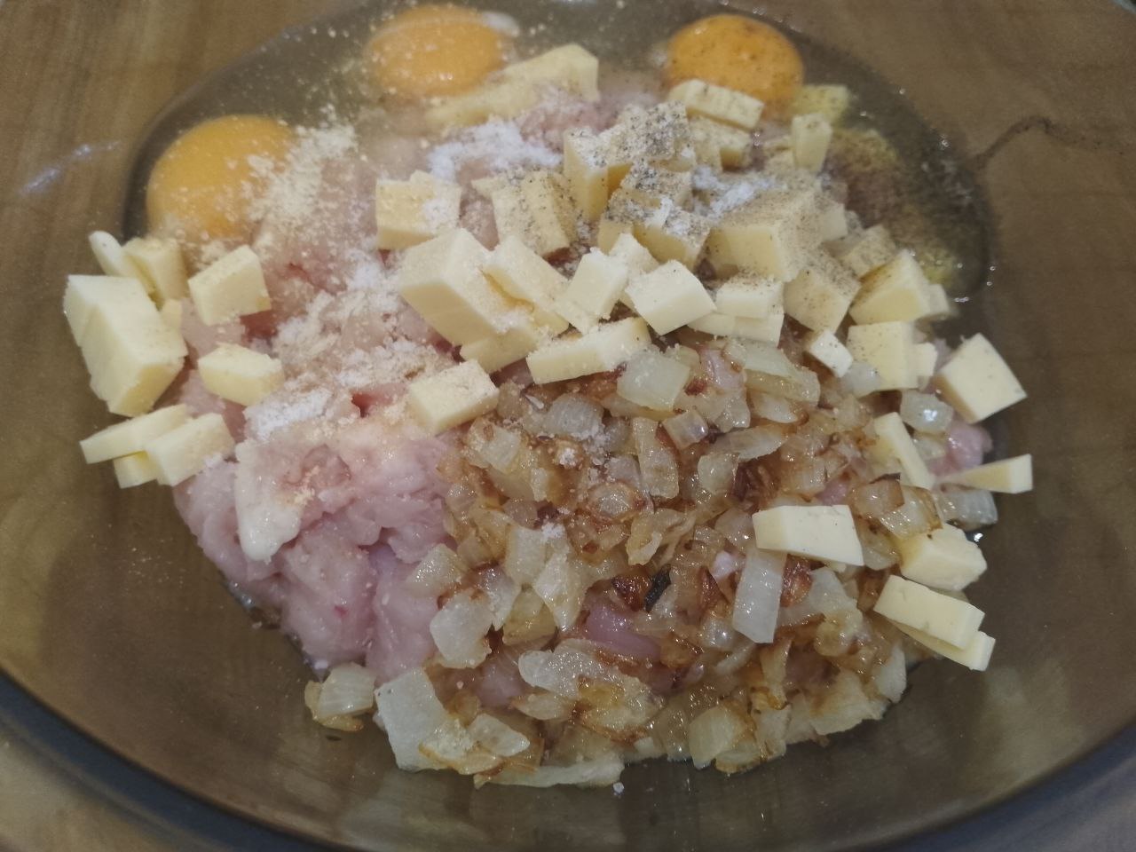 Котлеты из рубленого куриного мяса, сыра, запеченные в духовке: В миску или чашу кладем филе, обжаренный лук, кубики сыра и яйца. Добавляем по вкусу соль, перец и сухой