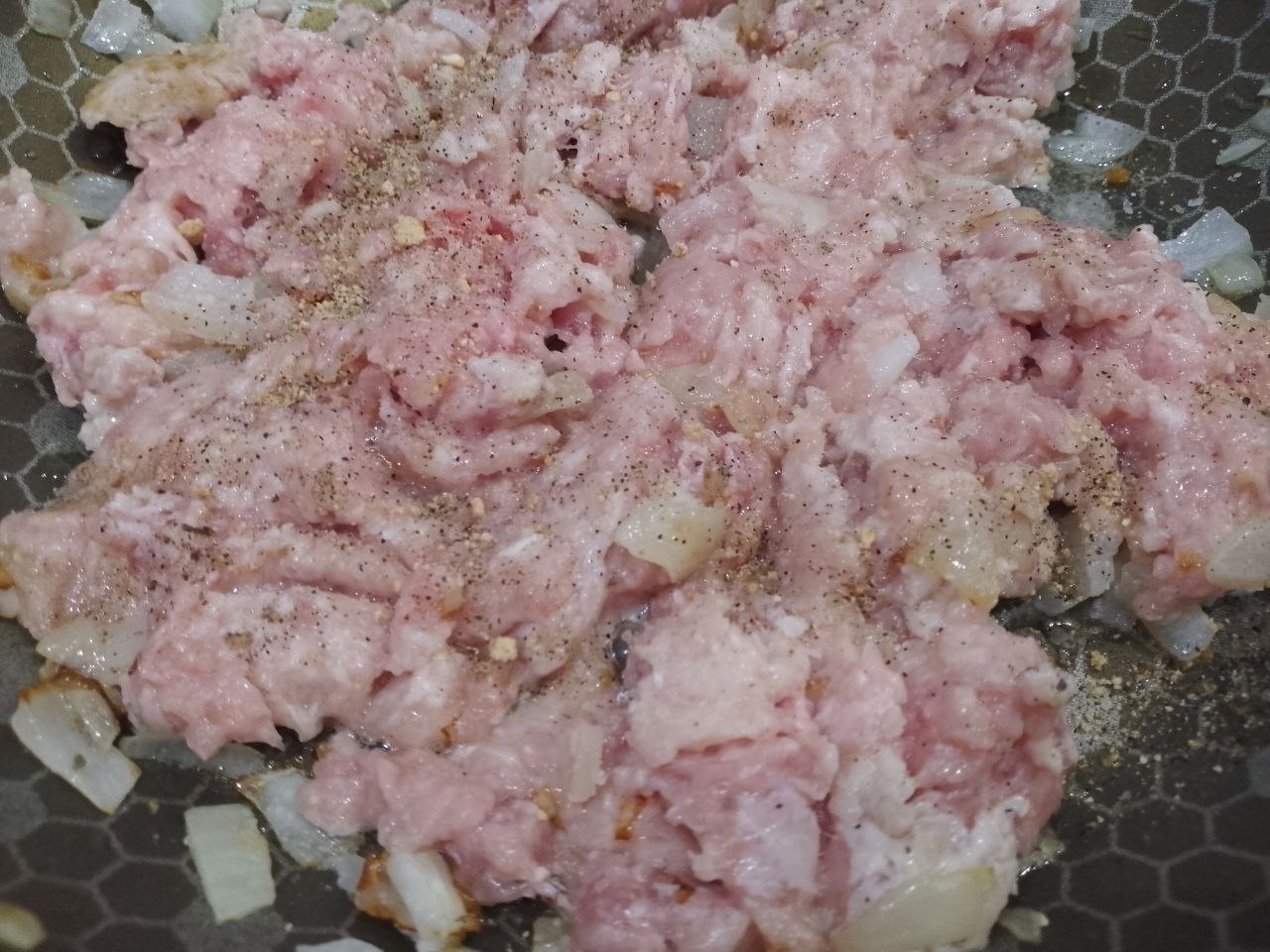 Рулет из тертого картофеля с мясной начинкой, запеченный в духовке: Добавляем фарш, солим, перчим и посыпаем чесноком, обжариваем до готовности.