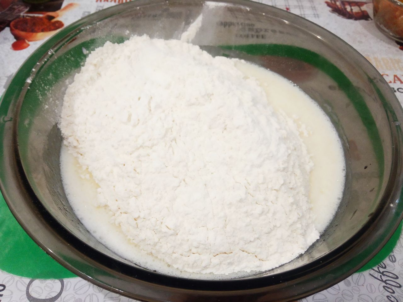 Мягкие и рассыпчатые булочки на кефире, с начинкой из тушеных яблок: Муку просеиваем через мелкое сито и соединяем с яичной смесью. Замешиваем мягкое и нежное тесто.
