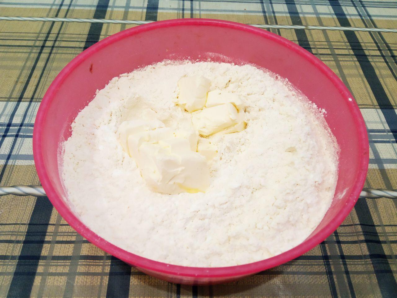 Домашнее печенье с кокосовой стружкой, рассыпчатое и песочное: Часть муки всыпаем в смесь, размешиваем и добавляем размягченное сливочное масло. Замешиваем мягкое и нежное