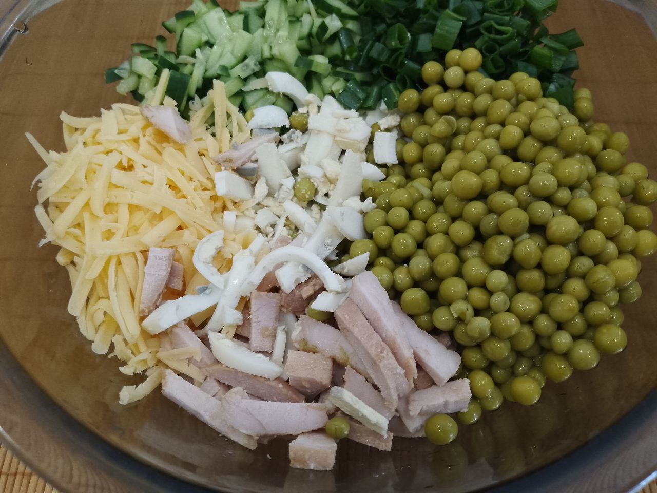 Салат с мясом, зеленым горошком и сухариками: В чаше соединяем мясо, сыр, зеленый горошек, зеленый лук, огурцы и яйца, перемешиваем.