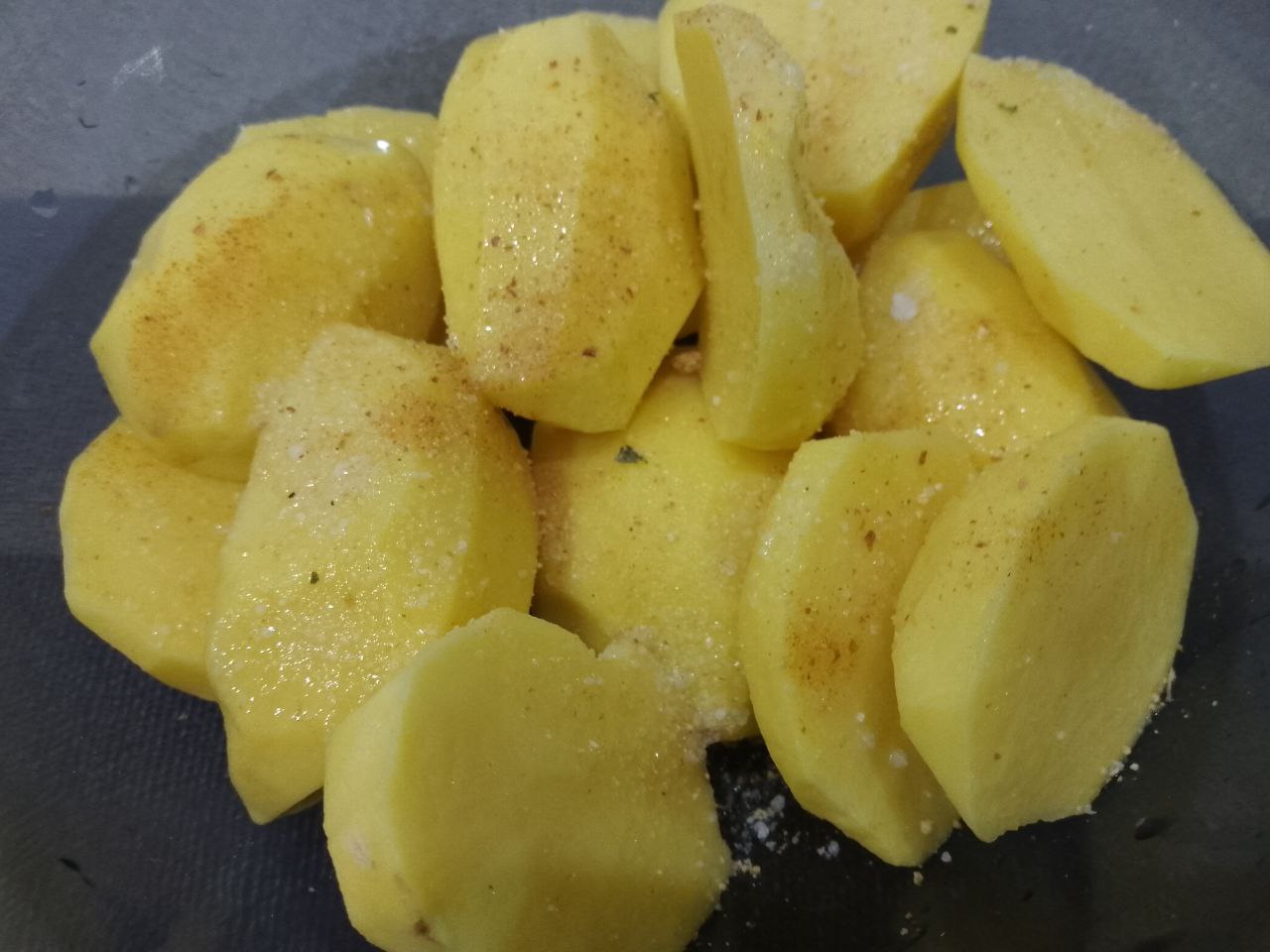 Картофель запеченный в духовке с грудинкой, просто и вкусно: Разрезаем картофель на две части, складываем в чашу, добавляем соль, перец и чеснок по вкусу, перемешиваем.