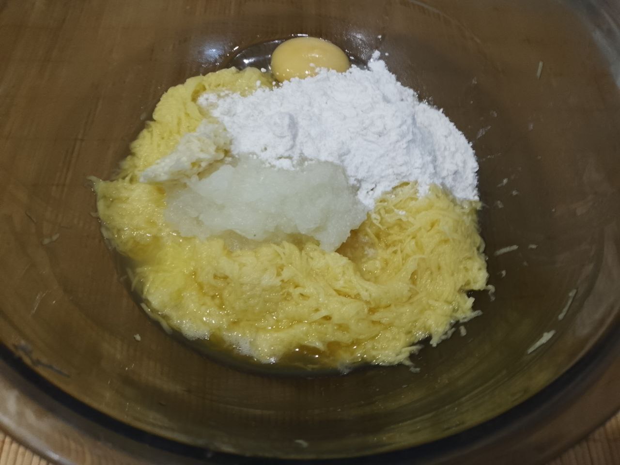 Драники с сыром, яйцом и сметаной: Картошку отжимаем, добавляем лук, чеснок, яйцо и муку, размешиваем.