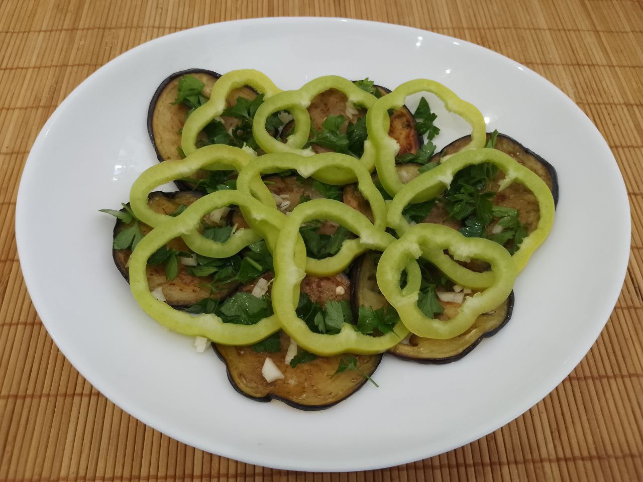 Салат из жареных баклажанов, помидоров, перца, чеснока и зелени, вкусный и аппетитный: Поверх петрушки выкладываем кружочки перца.