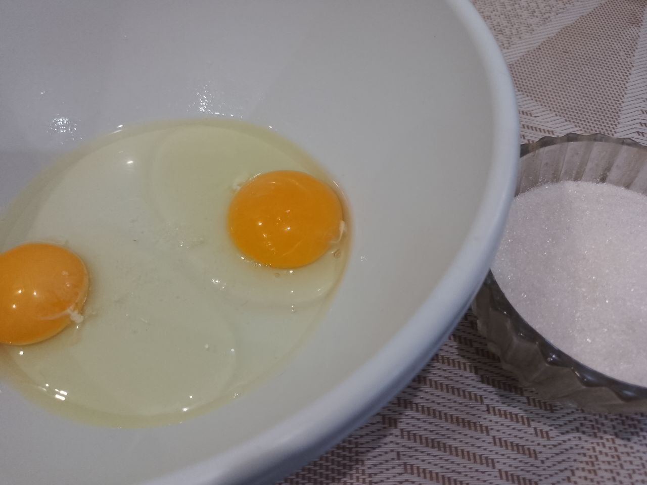 Печенье нежное и воздушное с вишней и кунжутом: В миску разбиваем яйца, добавляем сахар и ванильный сахар, взбиваем до загустения.