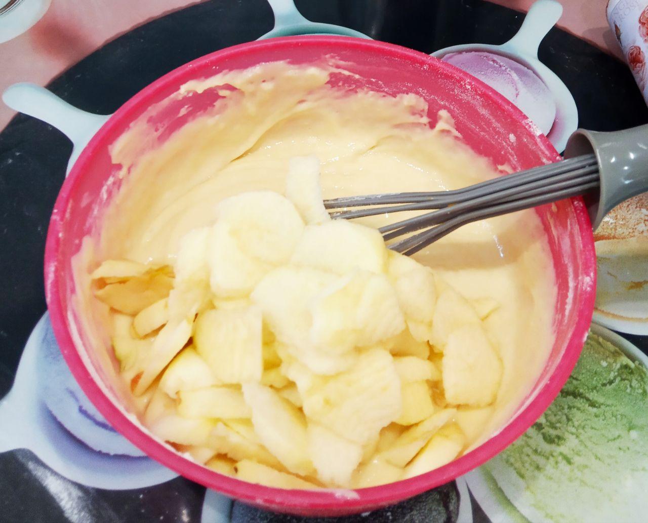 Простой рецепт яблочной шарлотки на кефире, быстро и вкусно: Пластинки яблок добавляем в тесто и перемешиваем, чтобы яблоки равномерно распределились в тесте.